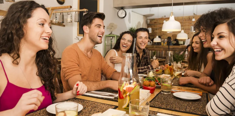 A group of people eating on a table | top loyalty programs for restaurants in 2022