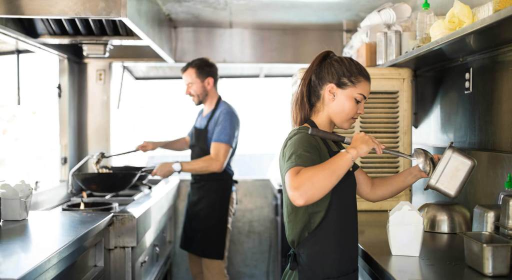 Staff cooking food inside a food truck  - Food truck management. 
